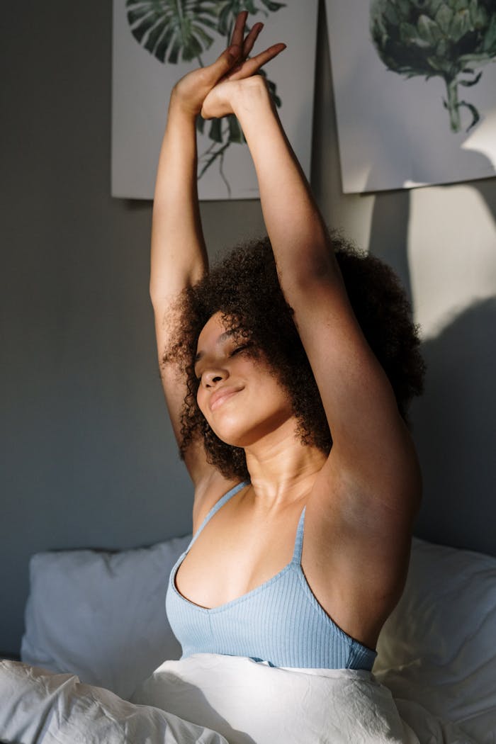 why-choose-us Woman with curly hair stretches joyfully in a sunny bedroom, embracing a peaceful morning.